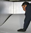 A contractor installing TerraBlock™ floor insulation in a Manchester crawl space