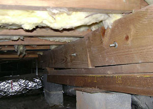 A sagging crawl space with concrete supports and wooden shimming a Cataula crawl space