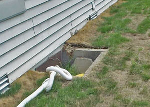 The ugly, old concrete window well of a Thomaston crawl space